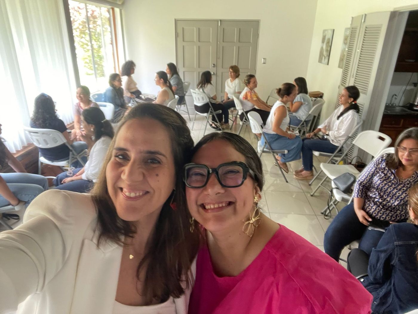 Ale y una co-facilitadora sonriendo frente a una sala llena de participantes